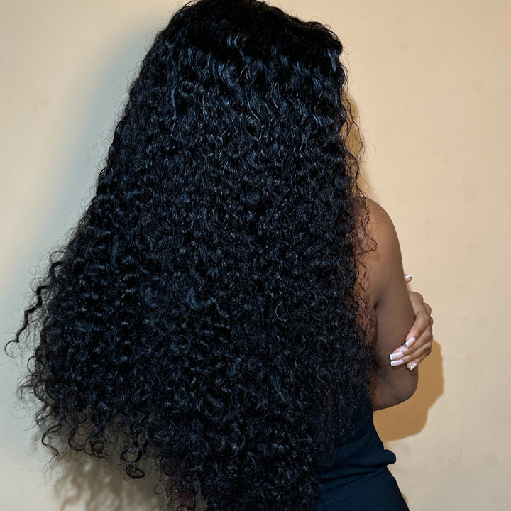 Person with long, curly black hair against a plain background