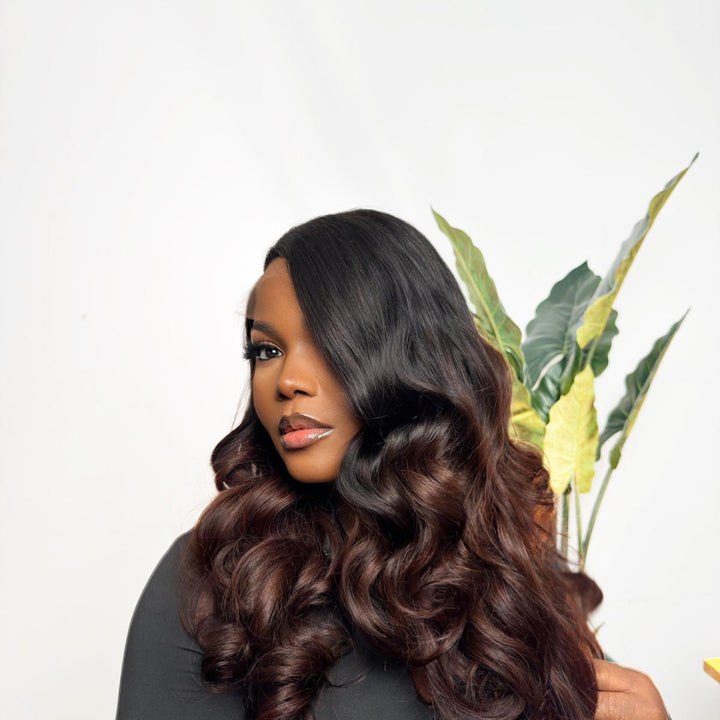 Woman with long, wavy hair holding a plant against a white background