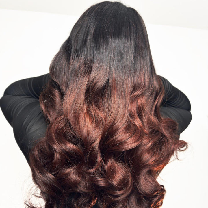 Person with long, wavy hair transitioning from black to brown on a white background